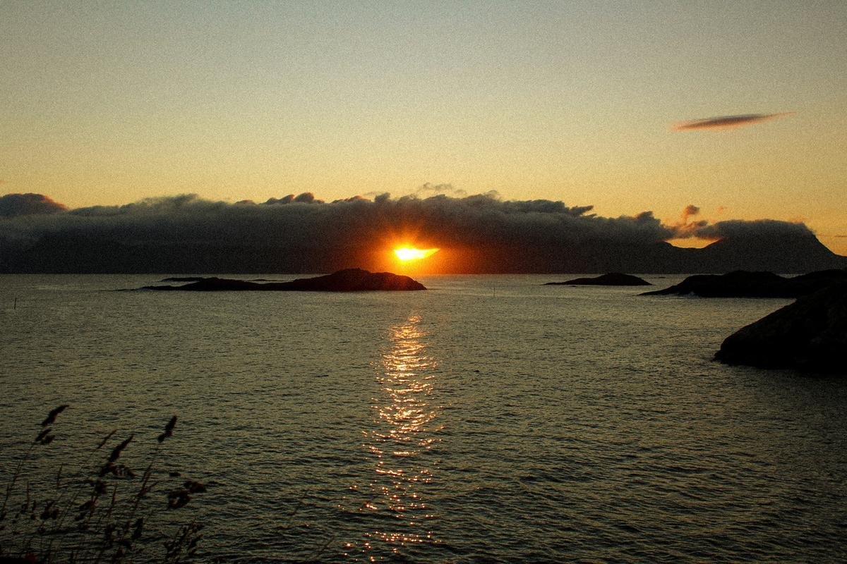 Midnight sun dipping over the sea and islands in Lofoten
