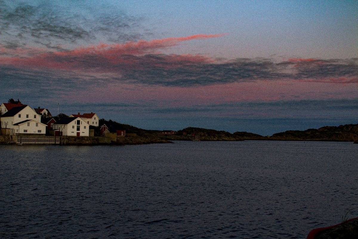 Pink clouds after dusk over the sea and houses in Lofoten